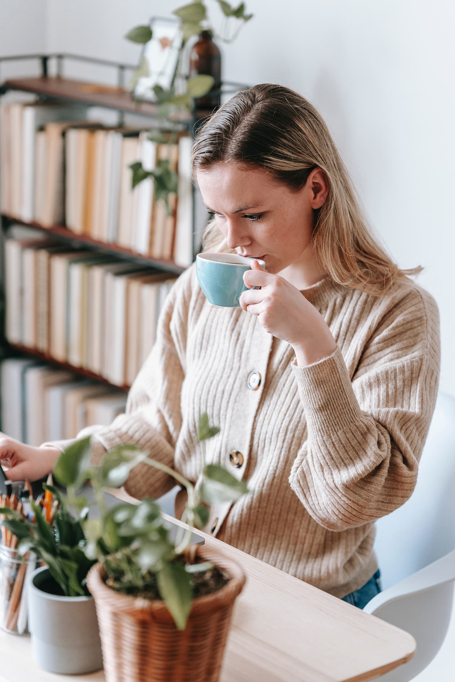 Woman in button-down sweater sitting at desk at home