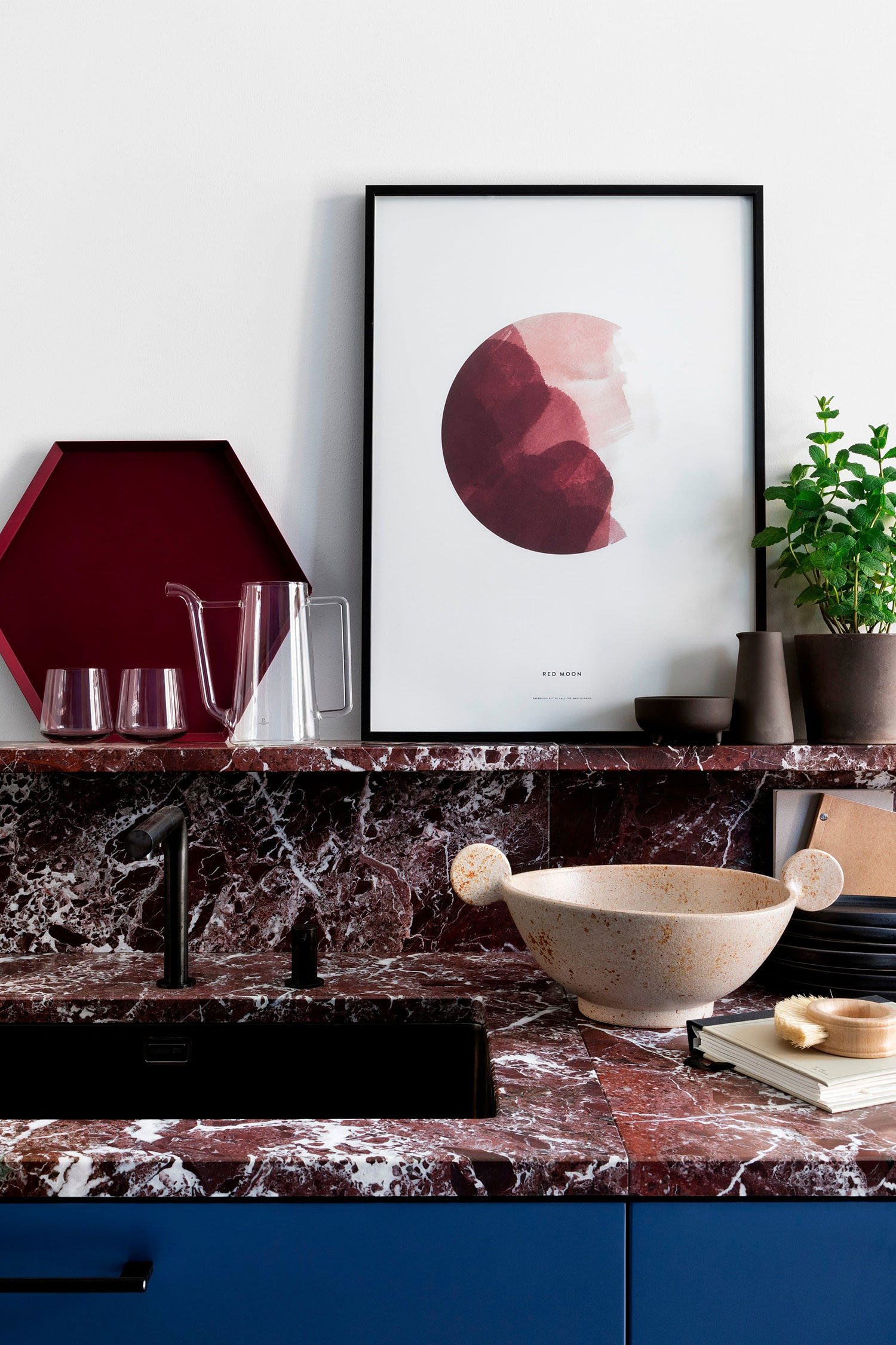 Detail of modern kitchen with red marble cooktop on which rests pretty wall art