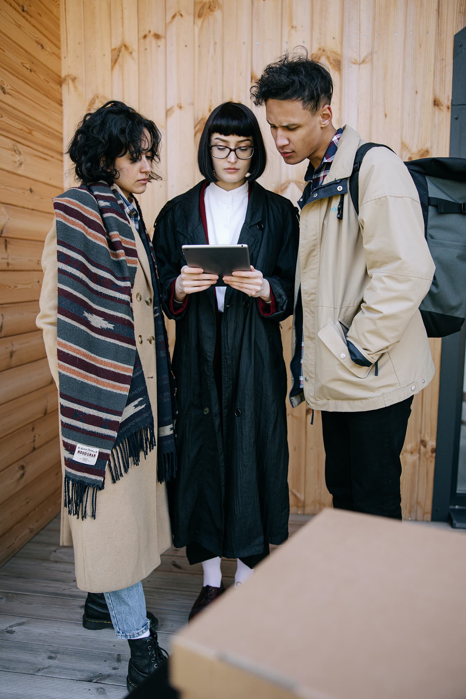 Woman in Black Coat Holding Tablet Beside Man in Brown Jacket and Woman in Brown Coat
